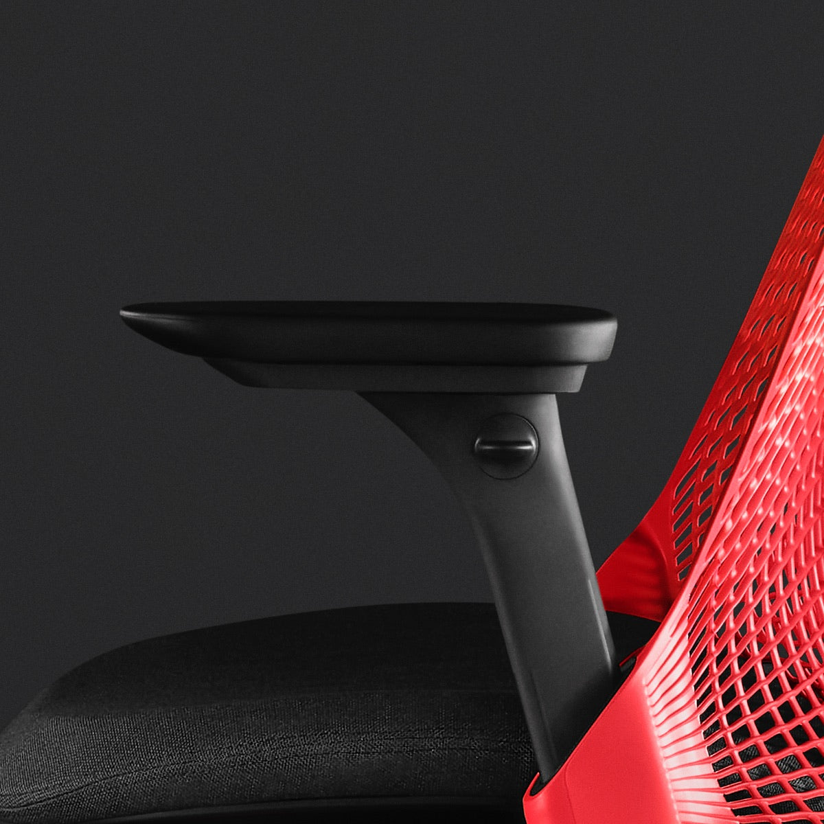 Vista laterale ravvicinata di una sedia da gioco Sayl rossa e nera di Herman Miller, che mostra i braccioli regolabili.